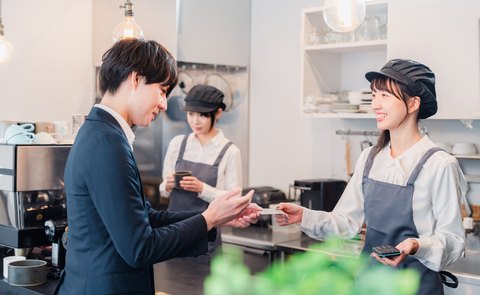 カウンターでキャッシュレス決済を受ける飲食店のスタッフ
